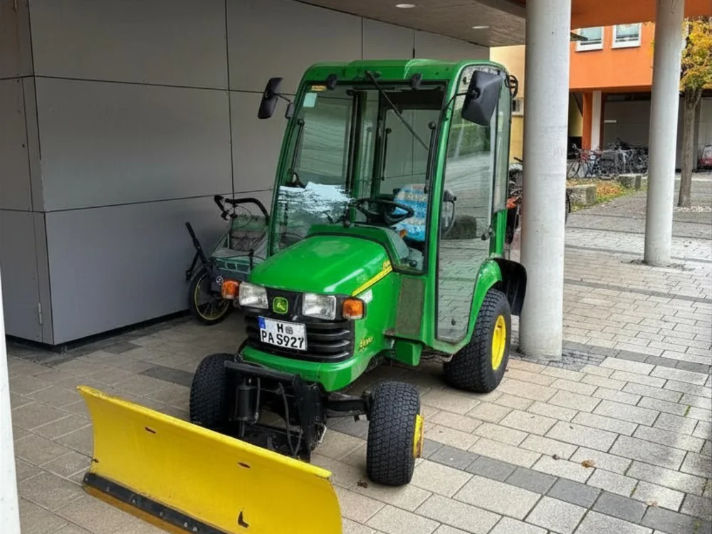Kompakttraktor mit Räumschild unter dem Carport einer Wohnanlage
