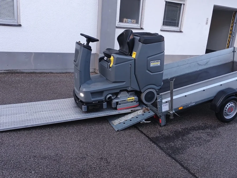 Aufsitz-Scheuersaugmaschine wird über eine Rampe vom Anhänger gefahren